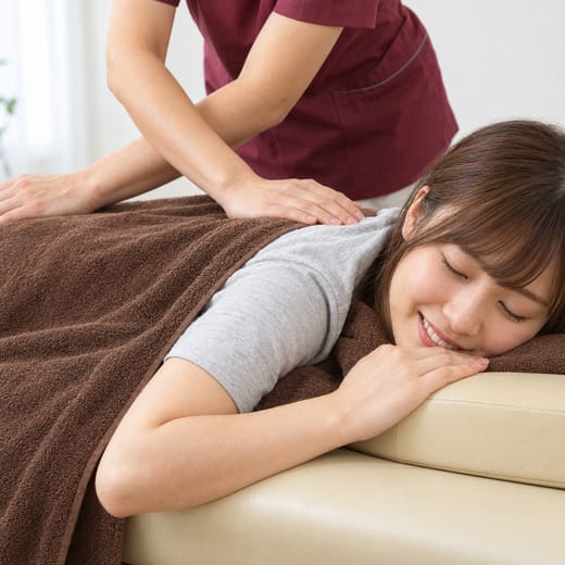 うつぶせで背中のマッサージを受ける女性(イメージ写真)